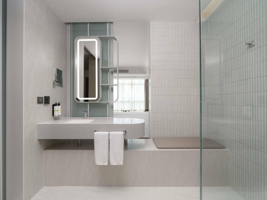 A modern bathroom with a large mirror, a sink, and a shower area.