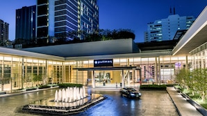 Entrada de hotel com uma fonte, arquitetura moderna e uma placa com a inscrição 'pulicn'.