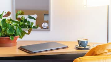 Een laptop op een houten tafel, een potplant en een koffiekop.