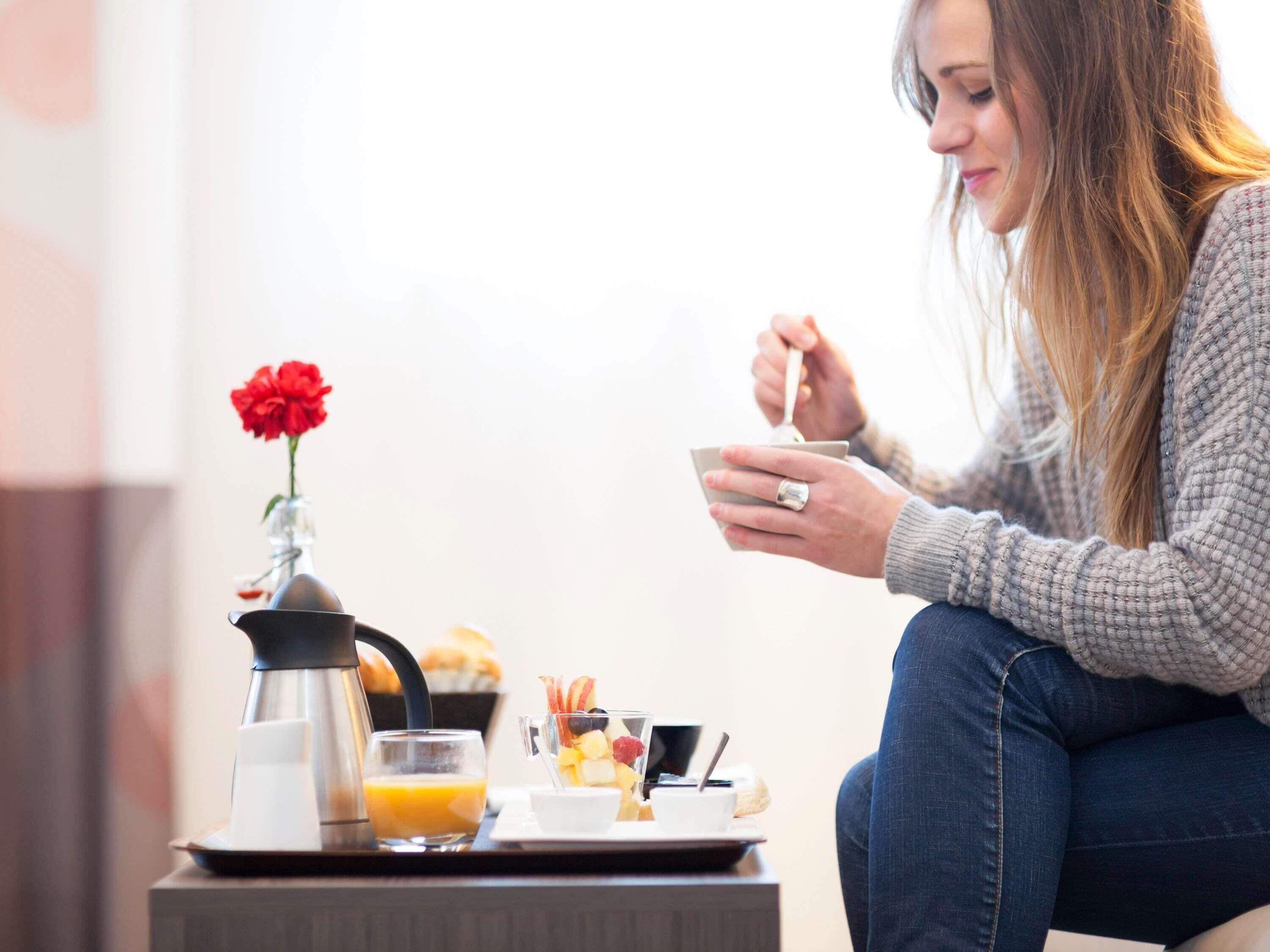 En frukostuppsättning med en kaffekanna, apelsinjuice och en fruktskål på ett bricka.