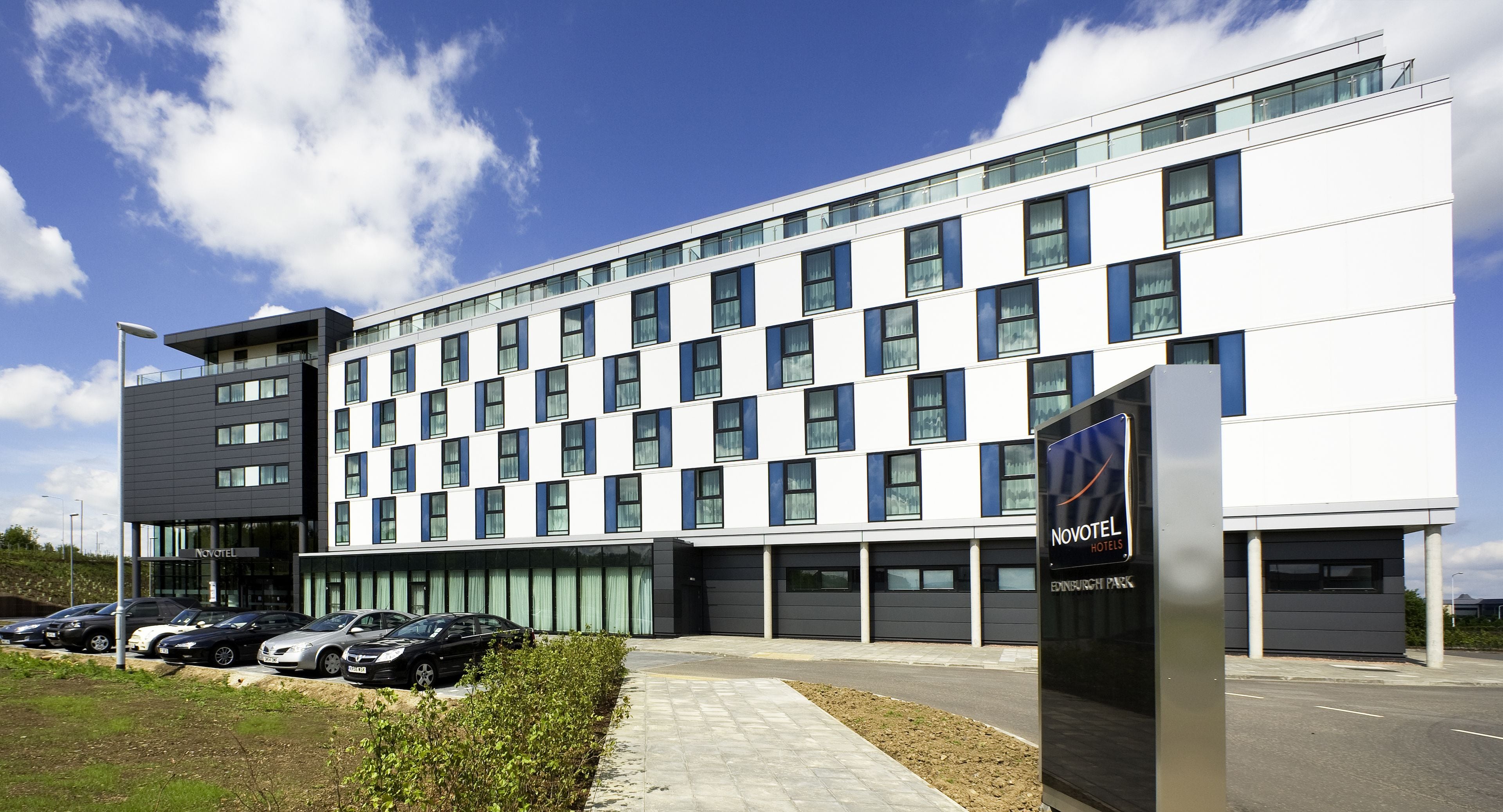 Un moderno edificio de hotel con una hilera de ventanas y un cartel que indica que es Novotel.