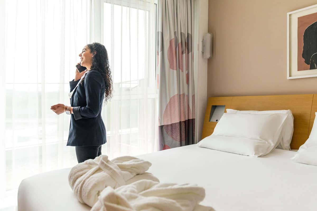 Ein Hotelzimmer mit Bett, einem Vorhangfenster und einem Bild an der Wand.