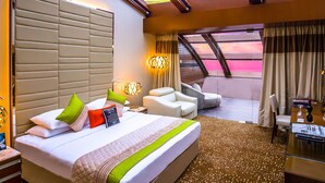 A modern hotel room with a large bed, a seating area, and a view of the sky through the ceiling. - Sahara Star (Mumbai)