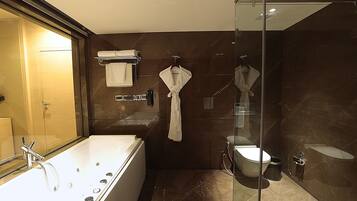 A modern bathroom with a large bathtub, a glass-enclosed shower, and a toilet.