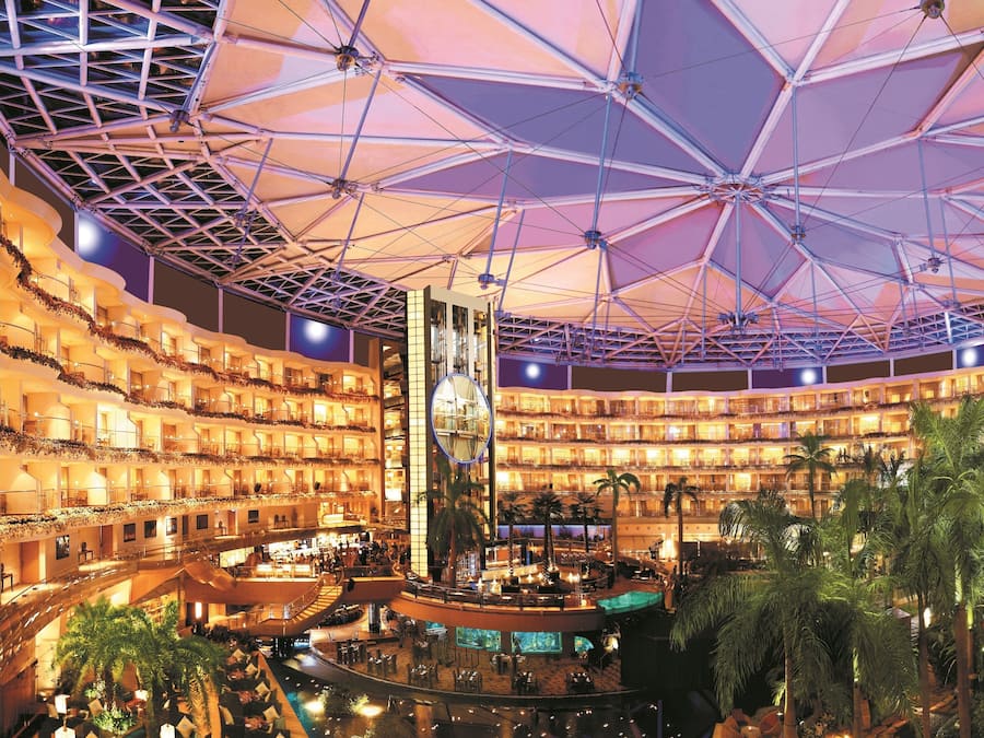 A multi-level hotel atrium with a central water feature, multiple balconies, and a large atrium ceiling.