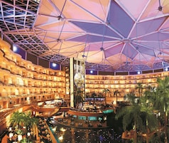 A multi-level hotel atrium with a central water feature, multiple balconies, and a large atrium ceiling.