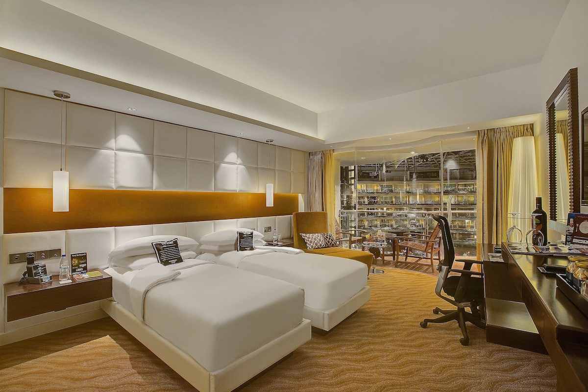 Une chambre d’hôtel avec deux lits, un bureau, une chaise et une vue sur la ville.