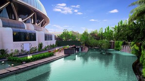 A modern building with a reflective facade, a water feature, and lush greenery. - Sahara Star (Mumbai)