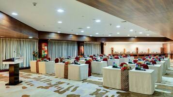 A conference room with multiple tables, chairs, and a podium.