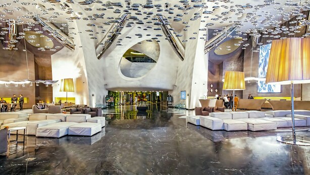 A spacious lobby with modern furniture, a reflective floor, and a unique ceiling design with hanging elements. - Sahara Star (Mumbai)