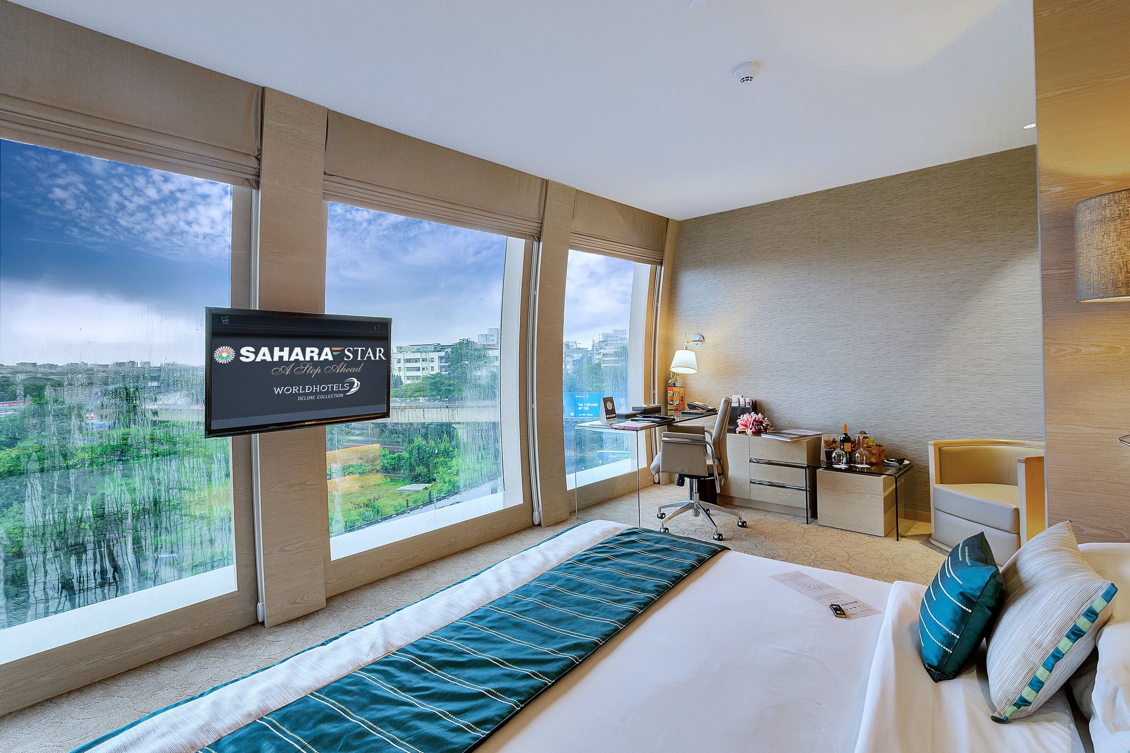 Una habitación de hotel con una cama grande, un escritorio y un televisor montado en la pared.