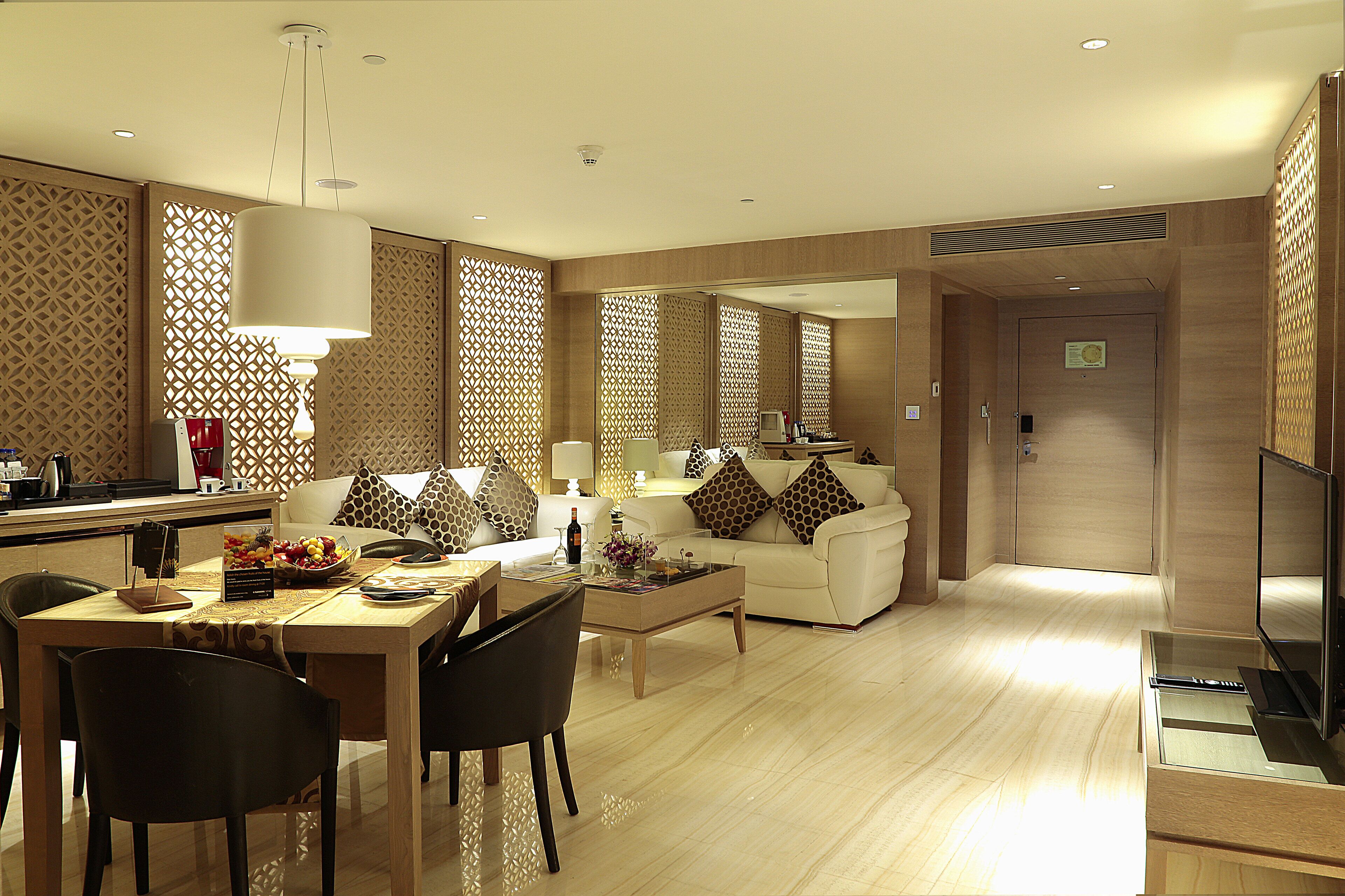 A modern hotel room with a dining area, a sofa set, and a TV.