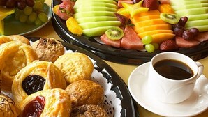 Una mesa con pasteles, fruta y una taza de café.