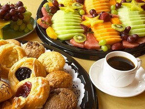 Una mesa con pasteles, fruta y una taza de café.