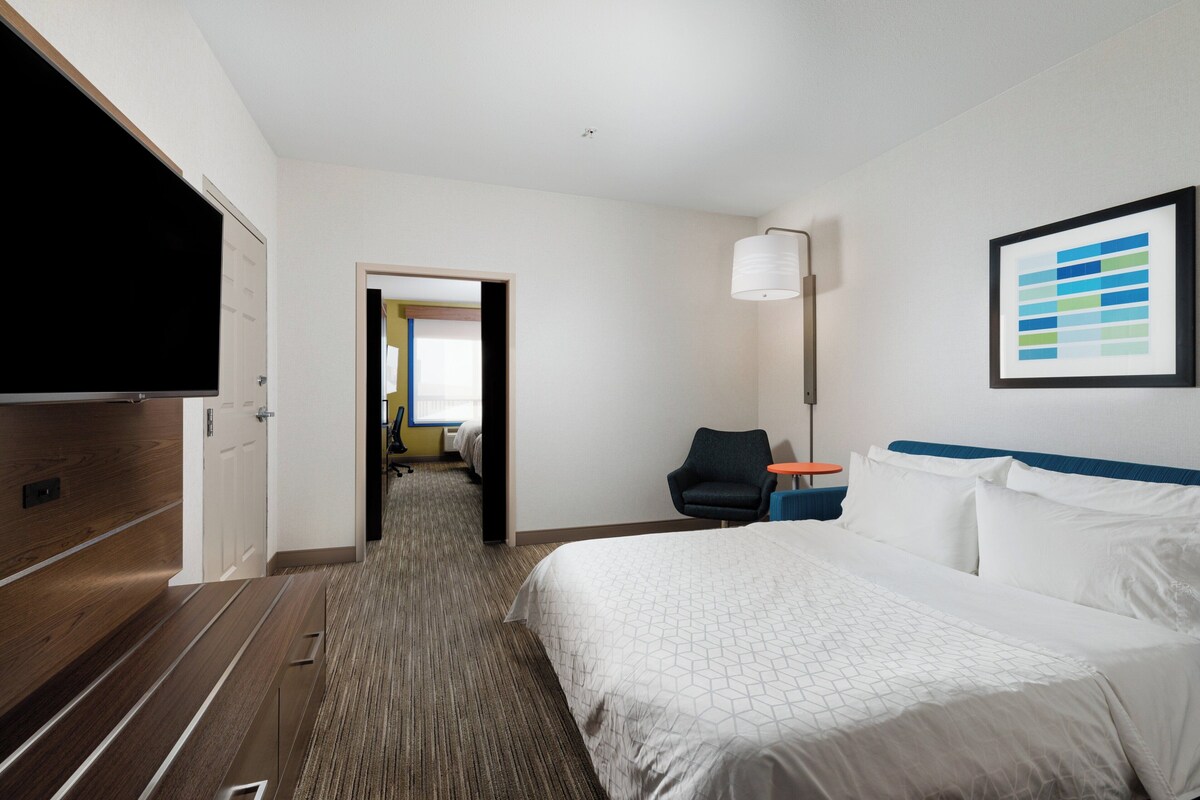 Una habitación de hotel con cama, televisión, escritorio y silla.