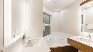 Un baño moderno con una bañera grande, dos lavamanos y un mueble de tocador de madera.