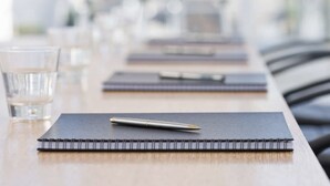 Una mesa de conferencias con libretas, bolígrafos y vasos de agua.