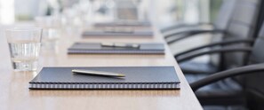 Una mesa de conferencias con libretas, bolígrafos y vasos de agua.