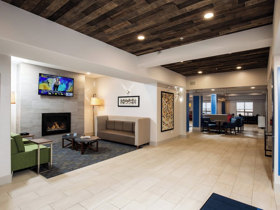 A spacious lobby with a fireplace, seating area, and a television displaying a weather forecast.