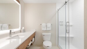 Un baño moderno con lavamanos, inodoro y ducha blancos.