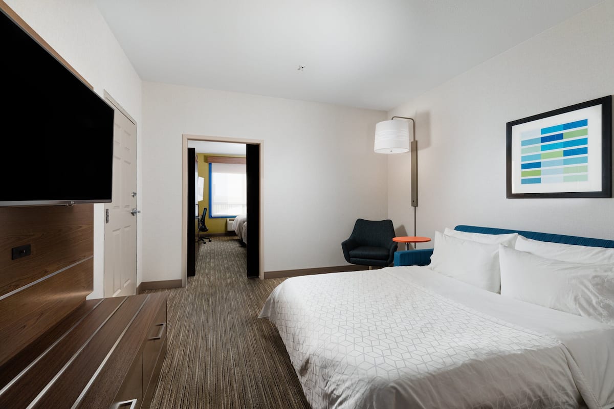 A hotel room with a bed, a TV, a desk, and a chair.