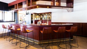 Een bar met een houten toonbank, barstoelen en een glazen vitrine.