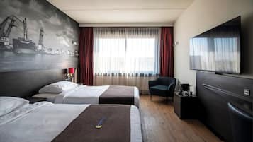 Habitación de hotel con dos camas, televisión, escritorio con cafetera y una silla.