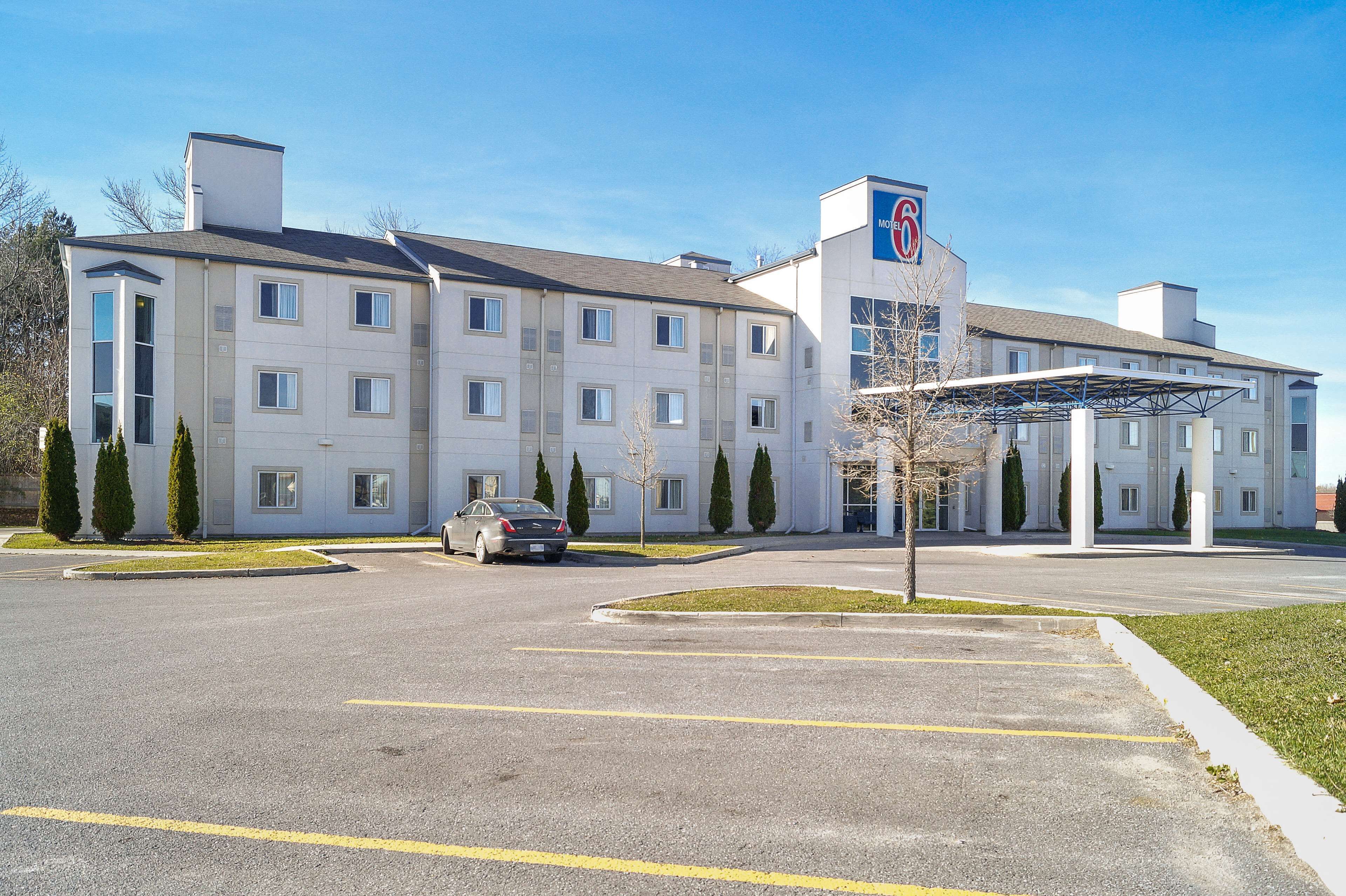 A multi-story hotel with a covered parking area and a car parked in front.
