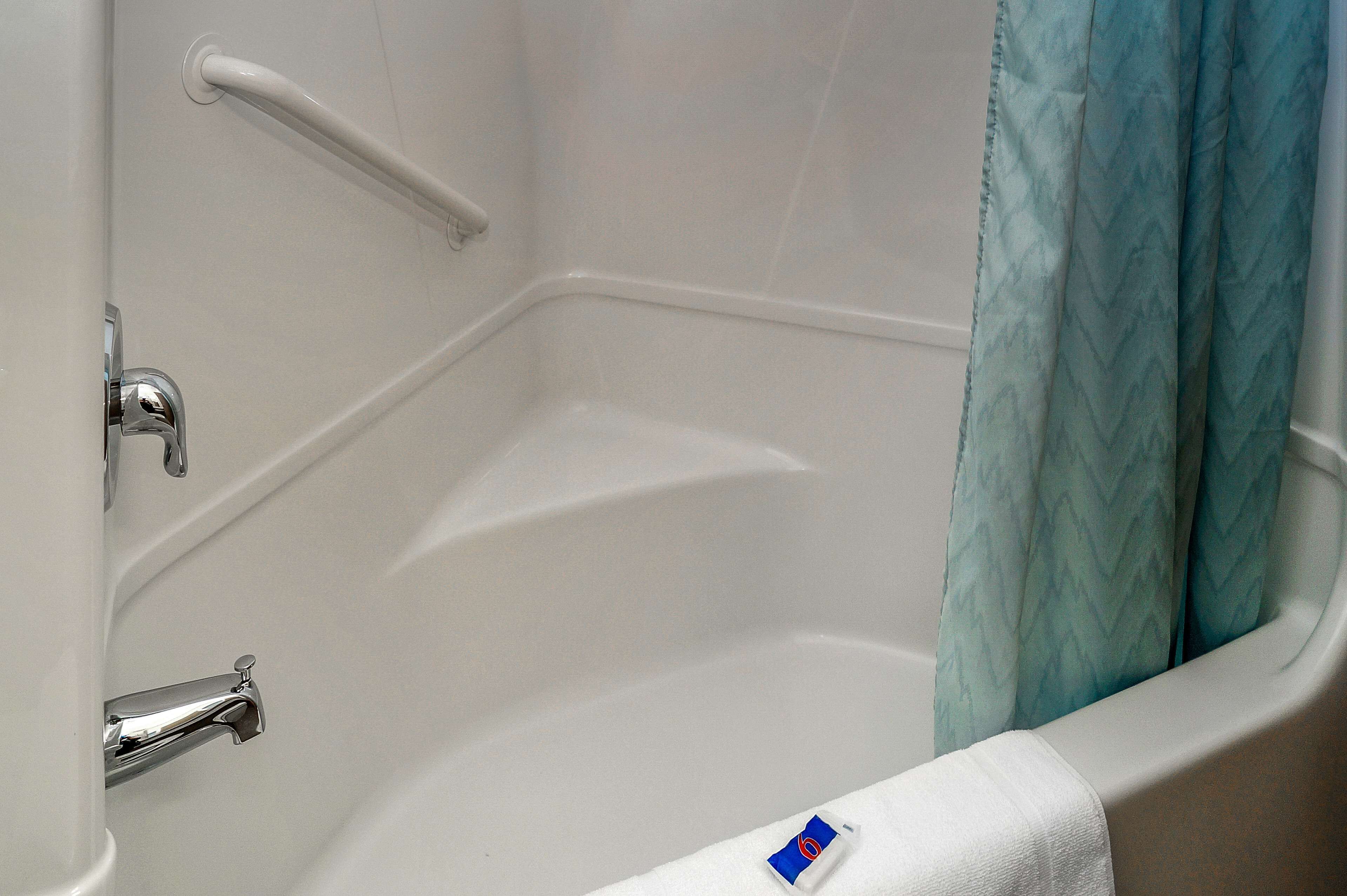 Eine Badewanne mit weiß gefliesten Wänden, einem Chrom-Wasserhahn und einem weißen Handtuch.