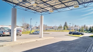 Un área de estacionamiento con sección cubierta, pilares de concreto y cielo despejado.