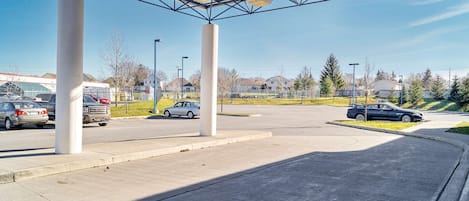 A parking area with a covered section, concrete pillars, and a clear sky.