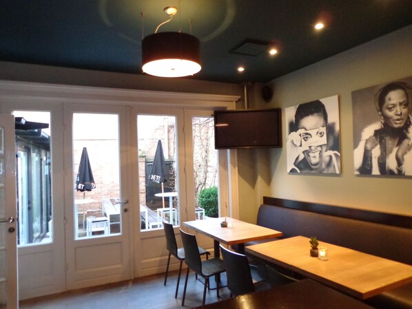 Interior de un restaurante con una zona de asientos tipo cabina, una mesa con sillas y un televisor en la pared.