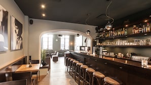 Een bar met krukken, een toog en planken met flessen en glazen.