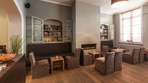 Een moderne lounge met zitplaatsen, een open haard en boekenkasten.