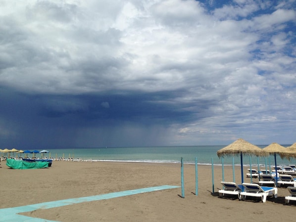 Une plage avec des transats et des parasols, un ciel dégagé et une mer calme.