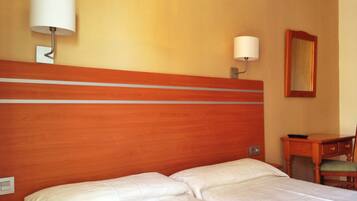 A hotel room with a wooden headboard, two beds, a desk, and a chair.