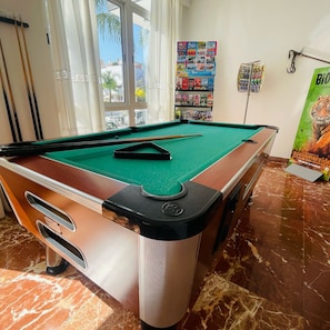 A pool table with a green felt surface, a pool cue, and a black pocket. - Hotel Carmen Teresa (Torremolinos)