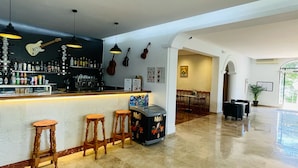 Un espace bar avec des tabourets, un comptoir avec des bouteilles et des éléments de décoration murale, notamment des guitares et un menu.