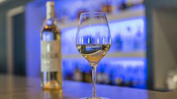 A glass of white wine and a bottle on a bar counter.