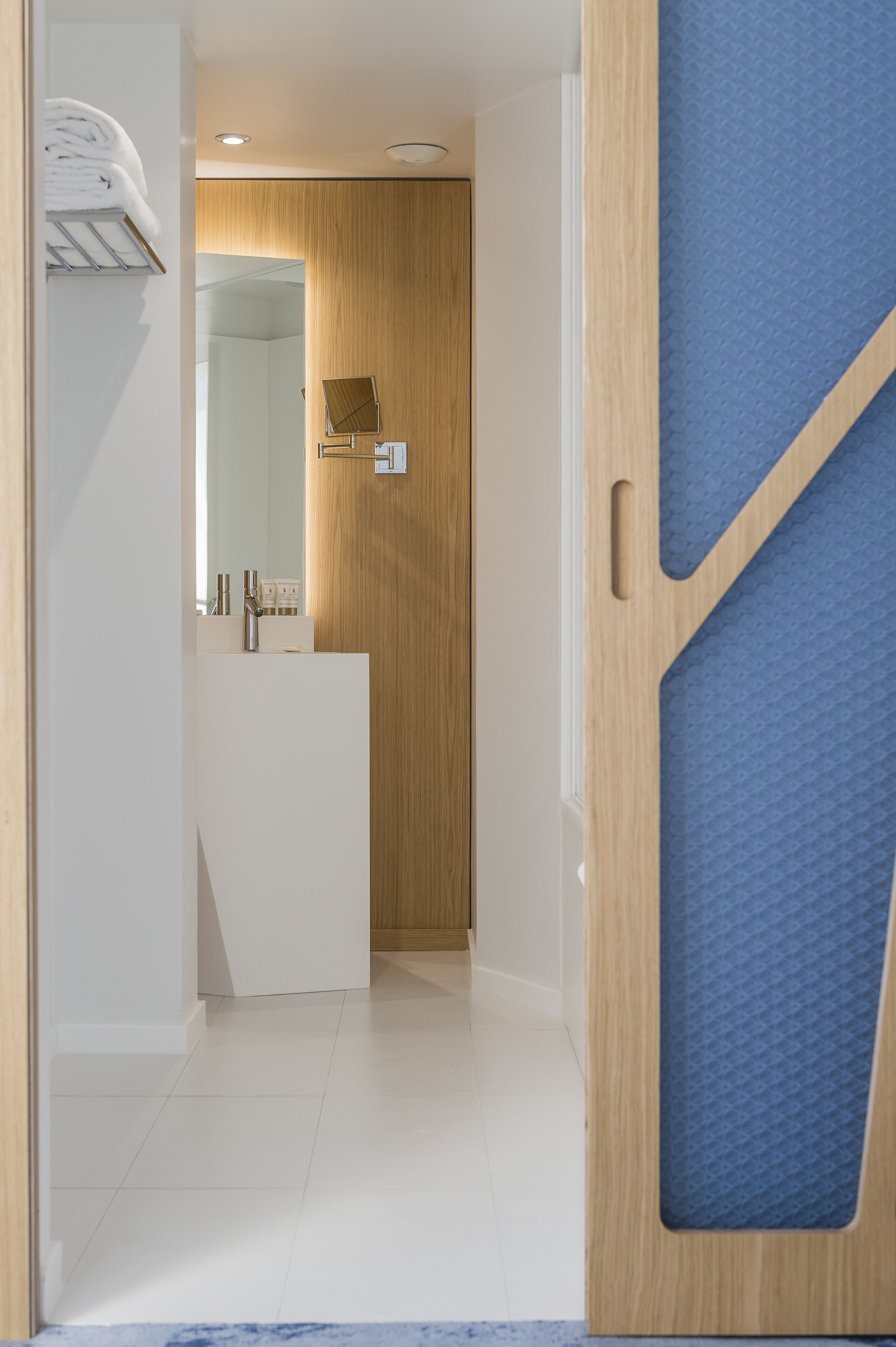 Een moderne badkamer met een houten wastafelmeubel, een spiegel en een handdoekhouder.