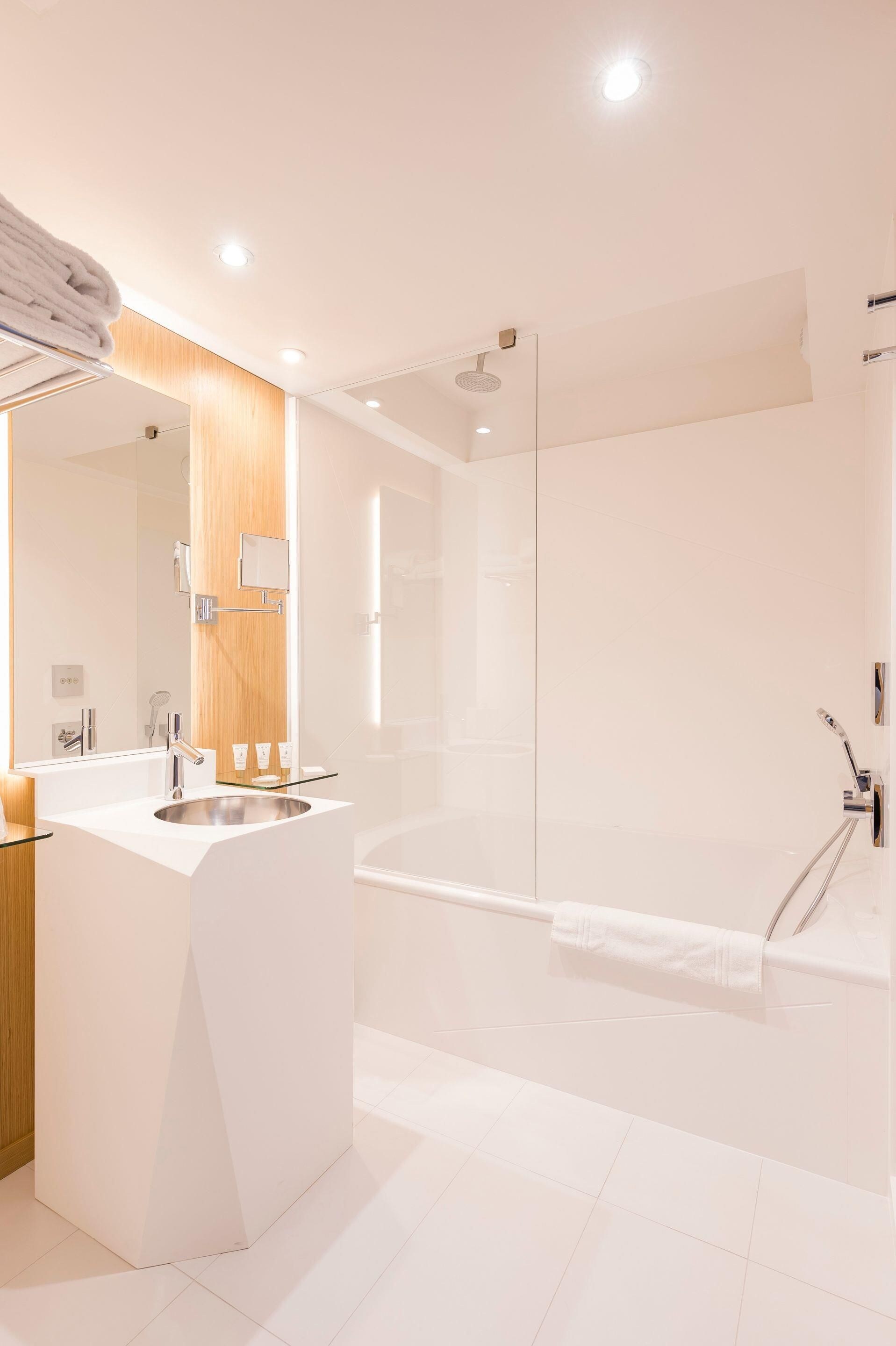 A modern bathroom with a glass-enclosed shower, a white vanity with a mirror, and a large mirror above the sink.