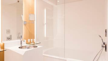 Un baño moderno con cabina de ducha de vidrio, un lavabo blanco con espejo y un mueble de tocador de madera.