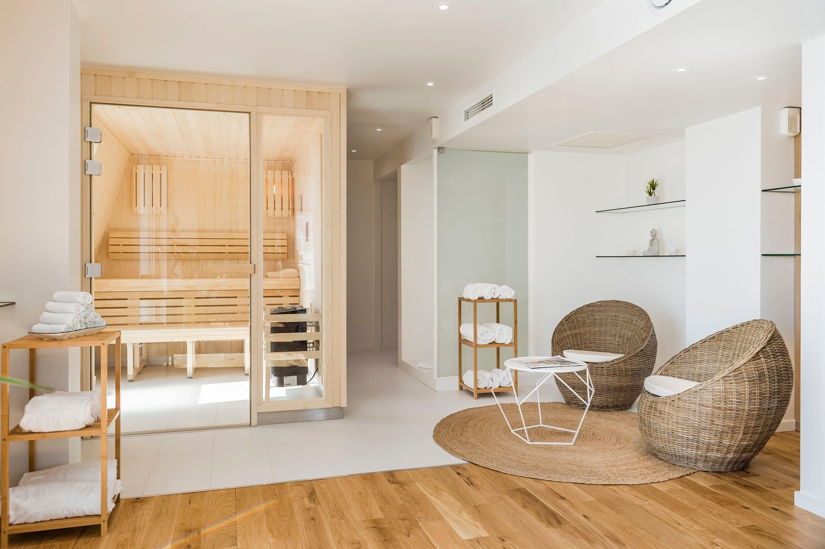 A modern bathroom with a wooden bench, a glass shower enclosure, and a small round table with a magazine.
