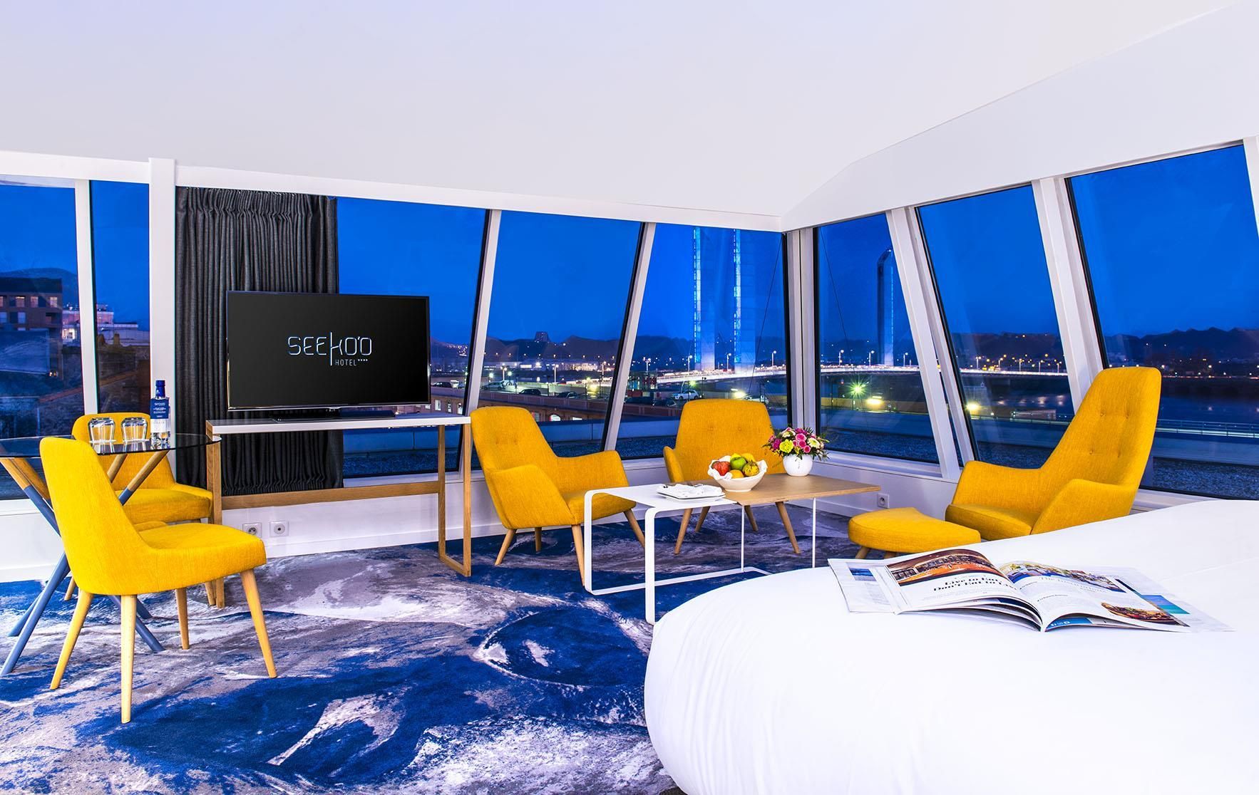 Una habitación de hotel moderna con una cama grande, televisión y vistas a la ciudad.