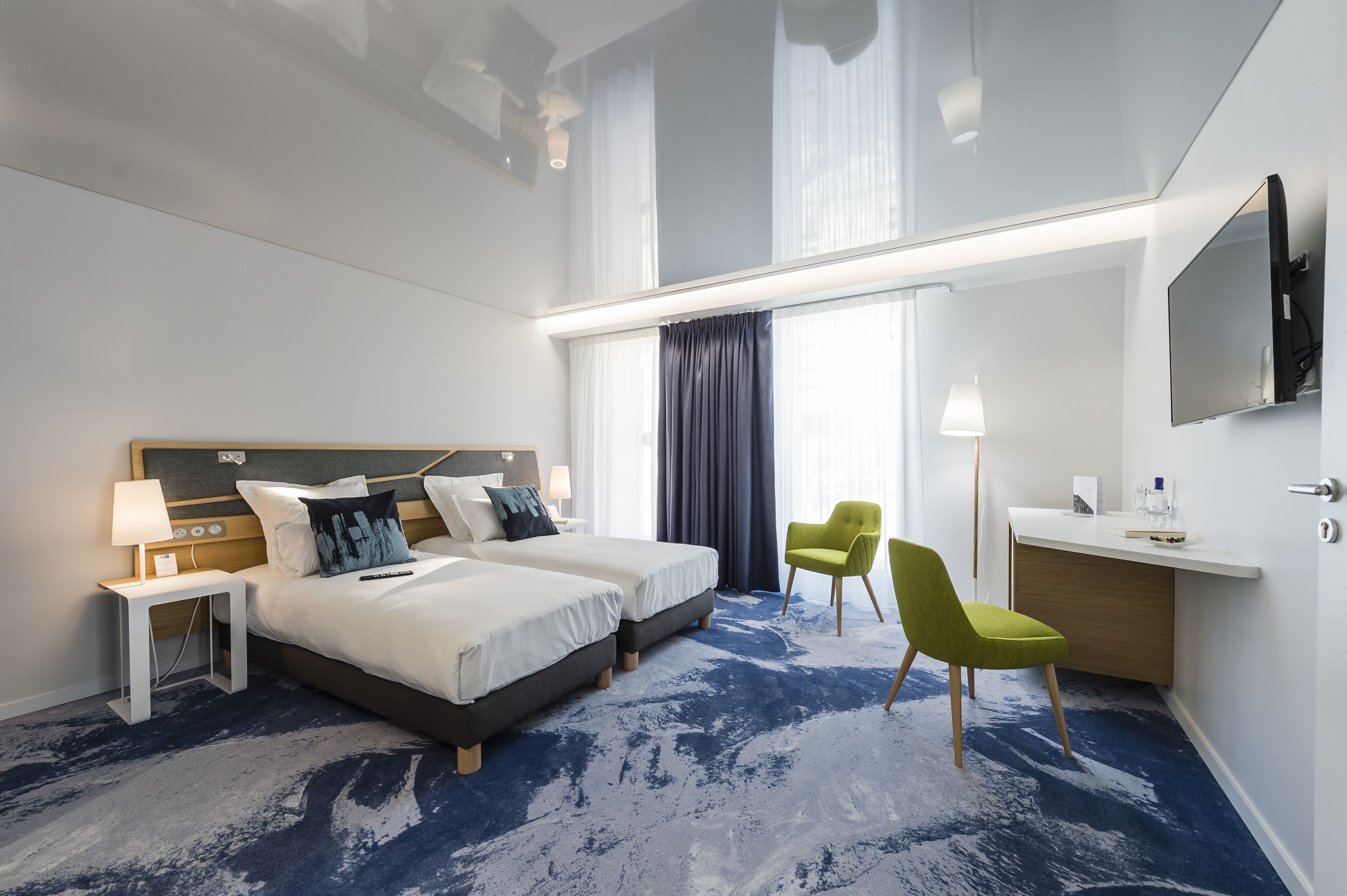 Een moderne hotelkamer met een groot bed, een bureau, een stoel en een televisie.