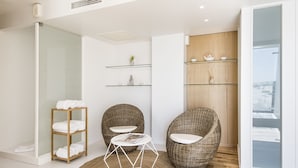Une salle de bain moderne avec des étagères en verre, des chaises en osier et une cabine de douche en verre.