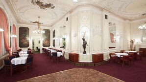 A grand dining hall with ornate ceiling details, multiple dining tables, and chairs arranged for service. - OREA Spa Hotel Palace Zvon Mariánské Lázně (Marianske Lazne)