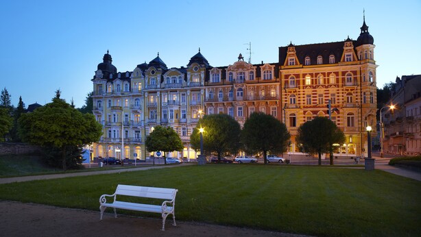 A historic building with ornate architecture, a grassy area with a bench, and street lamps. - OREA Spa Hotel Palace Zvon Mariánské Lázně (Marianske Lazne)