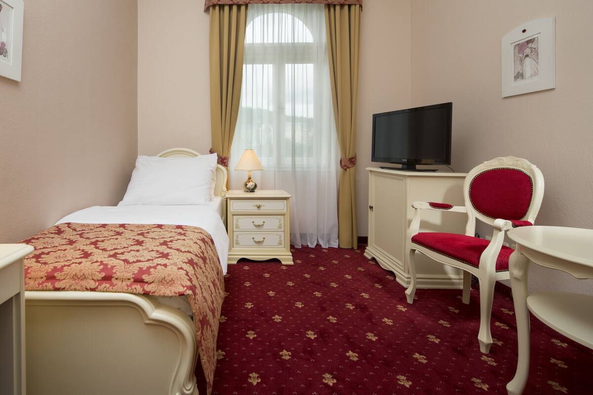 Une chambre d’hôtel avec un lit, une télévision, un bureau et une chaise.