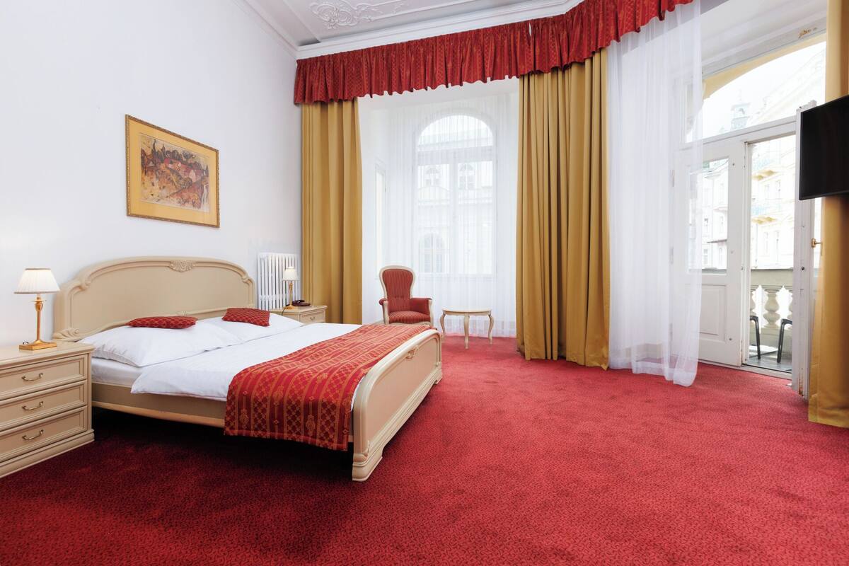 Une chambre d’hôtel avec un grand lit, une chaise, une table et un tableau au mur.